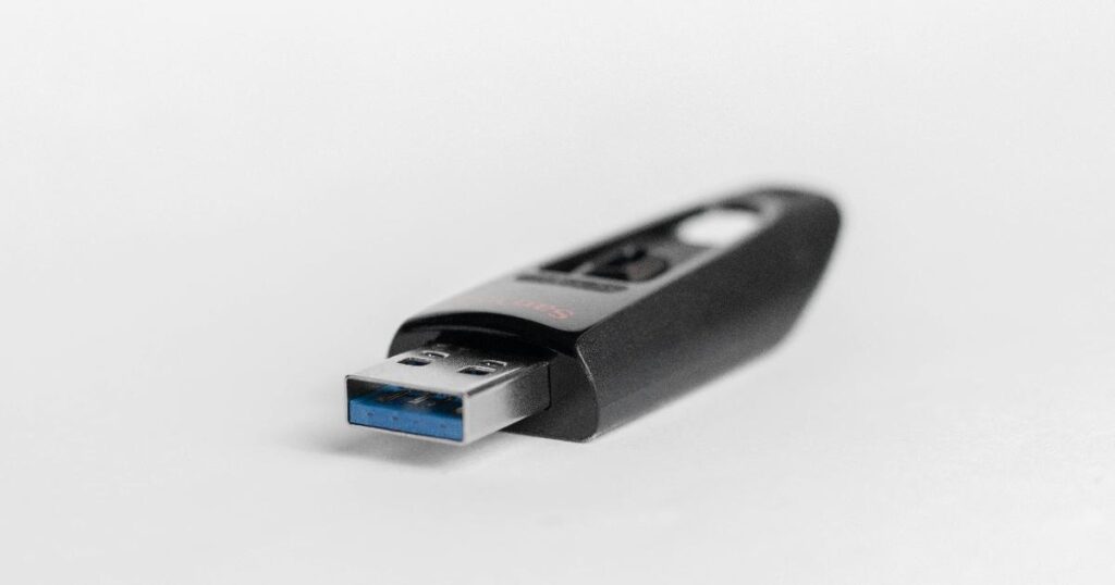A USB recovery drive beside a laptop, representing a Windows recovery drive used to repair boot problems